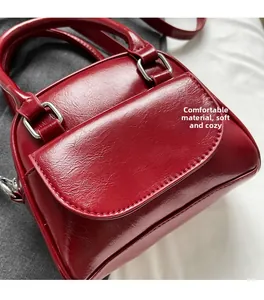 Detail of burgundy wax leather handbag with silver handle and soft material texture