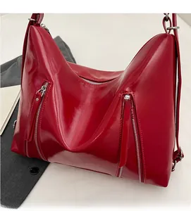 Detail of red glossy PU leather shoulder bag featuring silver zippers and modern style