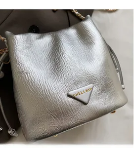 Detail of silver metallic bucket bag with floral texture and triangular metal logo
