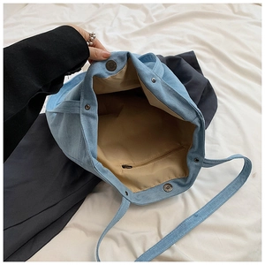 Interior detail of large denim tote bag showing magnetic snaps and zip pocket