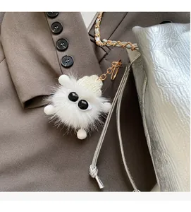 Close-up of white plush monster charm with knit hat on a silver chain bucket bag