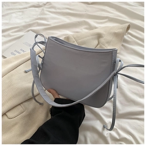 Détail du sac bandoulière en cuir bleu clair avec nœud de serrage et forme incurvée