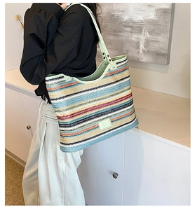 Detail of colorful striped woven tote bag featuring light green leather trim and shoulder straps