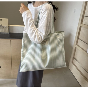Detail of green and white striped canvas tote bag showing the fabric texture and logo label