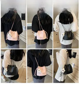 Detail of drawstring bucket bag featuring a metal chain strap and plush doll pendant