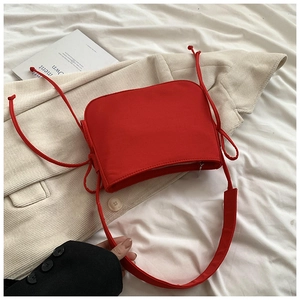 Détail du sac à bandoulière rouge en nylon avec fermeture éclair et cordons latéraux