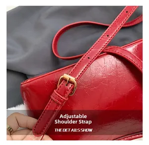 Detail of red glossy leather shoulder strap with adjustable golden metal buckle hardware