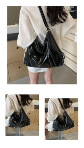 Detailed view of high-gloss black tote bag with decorative silver metal zippers