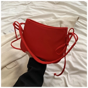 Détail du sac à bandoulière en nylon rouge vif avec fines lanières décoratives