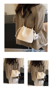 Detail of cream chain bucket bag showing textured leather and fuzzy ball pendant