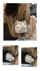 Detail of silver bucket bag with matte metallic texture, chain strap and plush pendant