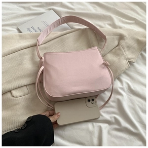 Sac à bandoulière en tissu rose avec sangle large à côté d'un smartphone de taille