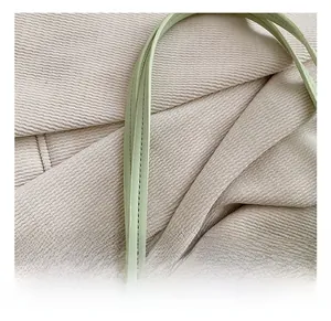 Detail of light green leather handle with fine stitching and silver rivets on corduroy bag