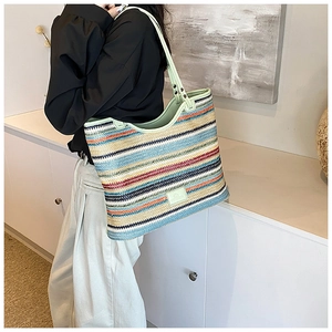 Detail of colorful striped woven tote bag with green leather straps and rivet accents
