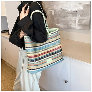 Close-up of colorful striped woven tote bag with green leather logo and slim shoulder straps