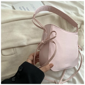 Vue détaillée du sac baguette en satin rose avec nœud coulissant et bandoulière large