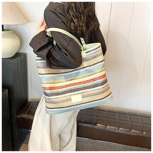 Detail of colorful woven tote bag featuring mint green leather straps and spacious interior
