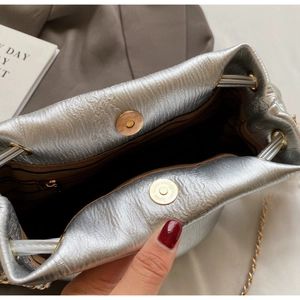 Interior detail of silver bucket bag showing magnetic clasp and brown striped fabric lining