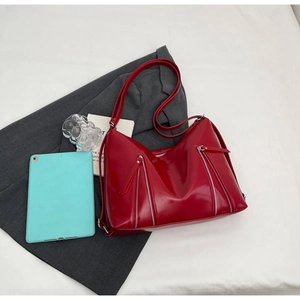 Detailed top view of a red shiny faux leather tote bag with parallel metal zippers