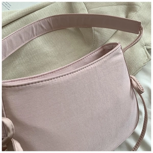 Gros plan d'un sac porté épaule en tissu rose montrant la texture et le nœud de la bandoulière