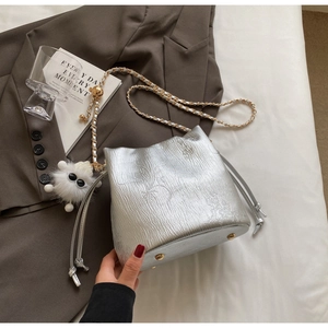 Detail of silver metallic bucket bag with leather chain strap and plush eye charm