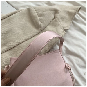 Détail d'un sac à main en tissu rose clair avec bandoulière large et nœud décoratif