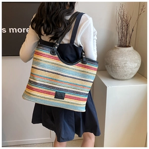 Close-up of colorful woven tote bag with striped pattern and black leather handles
