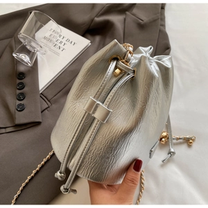 Detail of silver bucket bag with metallic crinkle texture and gold chain strap