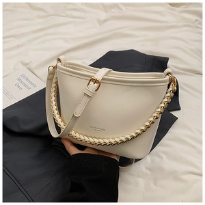 Detailed view of a white leather bucket bag featuring chain handle and gold lettering
