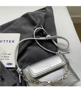 Close-up of metallic silver bucket bag featuring chunky metal chain and knotted rope strap