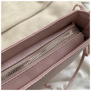 Détails macro d'une fermeture éclair en métal argenté et coutures sur un sac rose