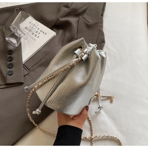 Top-down view of a metallic silver bucket bag with pleated texture and drawstring chain