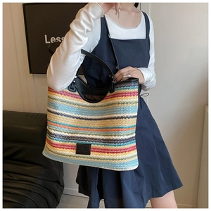Detail of colorful woven tote bag featuring striped pattern and black leather handles