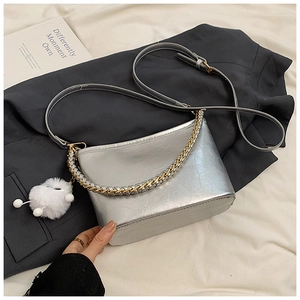 Close-up of silver textured leather crescent bag with chain and white plush pompom charm