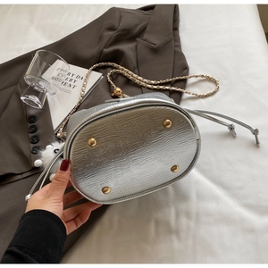 Macro view of silver bucket bag base with golden protective studs and textured leather