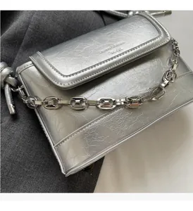 Macro shot of silver bucket bag with metallic crinkle texture and chunky chain strap