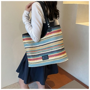 Detail of colorful woven tote bag featuring striped patterns and black leather shoulder straps