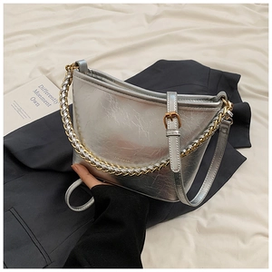 Detail of silver crescent shoulder bag featuring metallic chain and leather strap