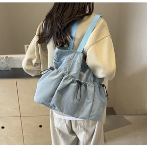 Blaue Nylon-Einkaufstasche mit Kordelzug und Schultergurt an einem Modell