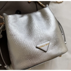 Detail of silver bucket bag with metallic crinkled texture, leaf embroidery and chain strap