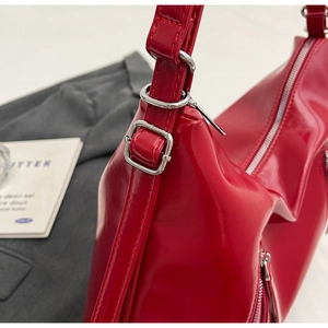 Detail of red glossy bow backpack with adjustable silver buckle and metallic zipper