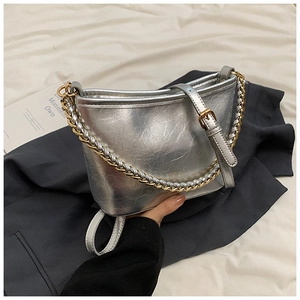 Detail of silver textured leather bucket bag featuring gold and silver braided chain