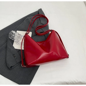 Detail of red glossy PU leather shoulder bag with adjustable strap and silver metal buckle