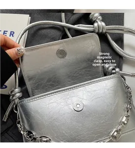 Detail of silver metallic bucket bag showing strong magnetic clasp and chain strap
