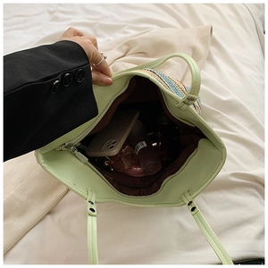Interior view of light green woven tote bag with brown lining and zipper pocket detail