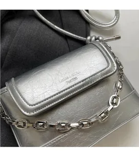 Macro detail of silver bucket bag with pleated texture and stylish metal chain strap