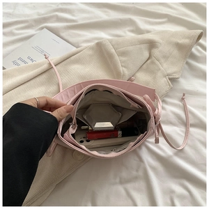 Vue intérieure du sac à bandoulière rose clair montrant sa capacité et sa poche zippée