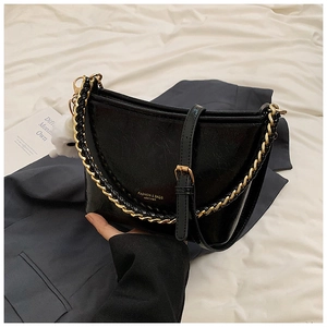 Detail of black glossy leather bag with gold chain strap and elegant gold logo text