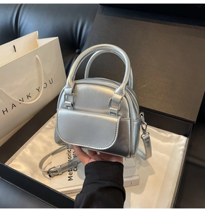 Silver shell-shaped mini handbag with metallic finish inside a black gift box