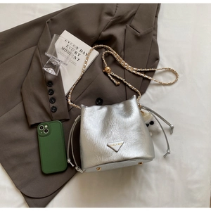 Detailed macro of silver bucket bag with metallic texture, gold chain and plush charm